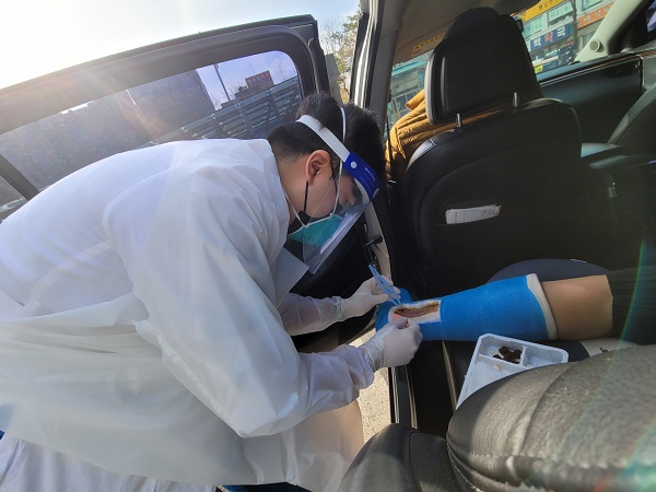 정형괴과 김경찬 전공의가 보호구를 착용하고 차량에서 환자를 치료하고 있다.