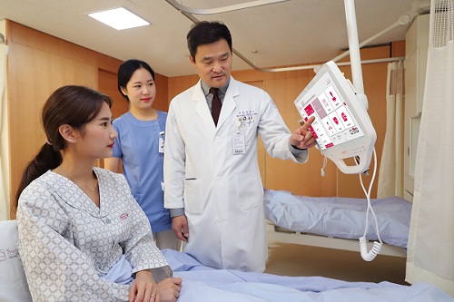 A tablet PC was installed 1:1 on an inpatient bed. The hospital director, Ho-seong Han, is explaining the treatment schedule to the patient while looking at the screen.